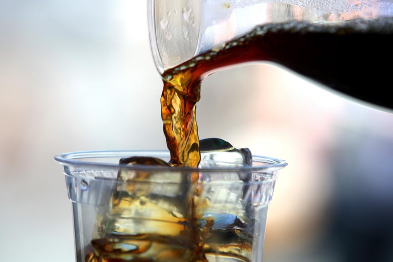 Coffee being poured into a cup with ice.